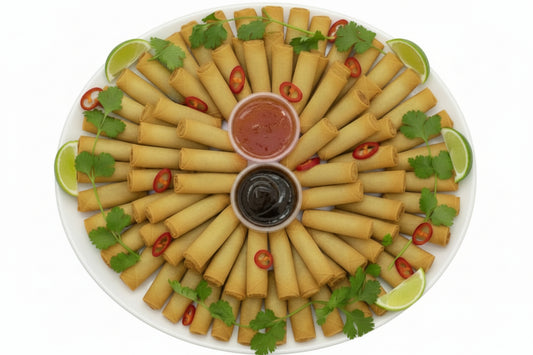 Platter of spring rolls with dipping sauces and garnishes on a white background